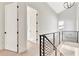 Upstairs hallway featuring black metal railing, modern chandelier, and natural light at 115 Arcadia Ave, Fayetteville, GA 30214