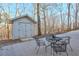 Small white outbuilding with double doors, nestled among trees, adjacent to an outdoor seating area at 8720 Rhapsody Ln, Cumming, GA 30041