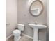 Cozy powder room featuring pedestal sink, toilet, and round decorative mirror at 1331 Penhurst Dr, Lawrenceville, GA 30043