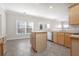 Well-lit kitchen boasts an island, stainless dishwasher, and natural wood cabinetry at 2124 Mitford Ct, Dacula, GA 30019