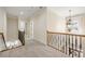 Upstairs hallway with carpeted floor, chandelier, and a wooden railing with iron spindles at 1734 Doonbeg Ct, Kennesaw, GA 30152
