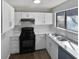 Modern kitchen with white cabinets, stainless steel sink, and a view through the window above the sink at 4673 Hairston Crossing Way, Stone Mountain, GA 30083