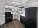Efficient kitchen with white cabinets, black appliances, and wood-look flooring at 4673 Hairston Crossing Way, Stone Mountain, GA 30083