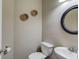 Powder room featuring a white toilet and sink with chrome fixtures, complemented by a round mirror and neutral wall decor at 1169 Harvest Brook Dr, Lawrenceville, GA 30043