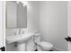 A well-lit bathroom featuring a modern pedestal sink and toilet with a contrasting door handle at 2140 Parkside Ln, Roswell, GA 30076