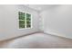 Bright bedroom featuring neutral carpet, crisp white walls, and a window offering a verdant outdoor view at 2140 Parkside Ln, Roswell, GA 30076