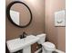 Stylish powder room with a sleek pedestal sink, black faucet and round mirror, exuding modern elegance at 208 Bastian Dr # 108, Villa Rica, GA 30180