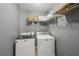 A modern laundry room with white washer and dryer, and shelving above at 4740 Arbor Meadows Dr, Cumming, GA 30040