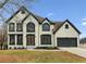 Charming two-story home featuring a mix of white and black trim, a gray garage door, and a well-manicured lawn at 4340 Boxwood Trl, Ellenwood, GA 30294