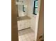 Bathroom featuring tiled floors, white cabinets, a sink, and mirror, with a window providing natural light at 1173 Mill Ridge Dr, Lawrenceville, GA 30045