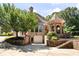 Stone house with a turret and a three car garage set amongst a manicured and mature landscape at 8480 St Marlo Fairway, Duluth, GA 30097