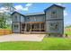 Spacious backyard showcasing a modern home with a covered deck, grassy area, and wood fence at 1400 Bouldercrest Rd, Atlanta, GA 30316