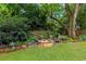 A charming stone fire pit with Adirondack chairs invites relaxation in a lush, landscaped backyard setting at 1518 Cambridge Ave, Atlanta, GA 30337