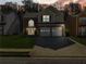 Charming two-story home with brick accents, attached two-car garage and manicured lawn at dusk at 2304 Stancrest Ln, Lawrenceville, GA 30044