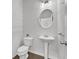 Compact powder room featuring a pedestal sink, round mirror, and neutral walls with wood flooring at 4362 White Spruce Aly, Doraville, GA 30360