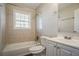 Bathroom featuring a tub/shower combo, window, toilet, vanity, and tile surround at 1932 Rosewood Rd, Decatur, GA 30032