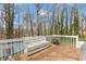 View of the outdoor wooden deck featuring a bench and table surrounded by a wooded area at 67 Oak Landing Way, Douglasville, GA 30134
