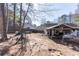 Large, unfinished backyard with a covered patio area, surrounded by tall trees and a wooden fence at 975 Fox Valley Trl, Stone Mountain, GA 30088