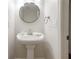 Cozy pedestal sink in a bathroom with a round mirror and chrome fixtures at 110 Great Oaks Ln, Roswell, GA 30075