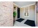 Inviting front porch with a black door, brick accents, and a stylish outdoor light fixture at 110 Great Oaks Ln, Roswell, GA 30075