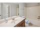 A bathroom with a shower-tub combo, a sink with a wooden cabinet, and light-colored walls at 1502 Park Hollow Ln, Lawrenceville, GA 30043