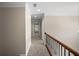 Hallway with neutral walls, carpet, and a wooden railing, leading to a window in the distance at 1502 Park Hollow Ln, Lawrenceville, GA 30043