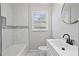 Modern bathroom features white tiled walls and flooring, black fixtures, and a large mirror above the vanity at 2478 Graywall St, Atlanta, GA 30344