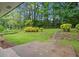Grassy backyard with mature trees and a small patio area at 2478 Graywall St, East Point, GA 30344