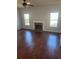 Living room boasts wood laminate flooring, a ceiling fan, fireplace, and natural light from two windows at 1546 Mine Run, Hampton, GA 30228