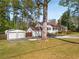 A charming white home with a detached garage sits among mature trees and a spacious front yard at 4100 Brown Rd, Tucker, GA 30084