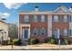 Charming brick townhome with a blue front door, well-maintained landscaping, and symmetrical window design at 5968 Eagle Tiff Ln, Sugar Hill, GA 30518