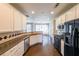 Bright kitchen with white cabinetry, a dark countertop, stainless steel dishwasher, and black appliances at 349 Azalea Chase Dr, Suwanee, GA 30024