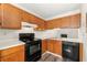 Well-lit kitchen featuring black appliances, wooden cabinetry, and a view to living space at 858 Heritage Valley Rd, Norcross, GA 30093