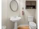 Elegant half bathroom features a pedestal sink, decorative mirror, and hardwood floors at 2915 Pruitt Rd, Cumming, GA 30041