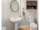 Charming powder room with a pedestal sink, oval mirror, and modern toilet at 2915 Pruitt Rd, Cumming, GA 30041