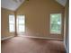 Large primary bedroom featuring vaulted ceiling, plush carpeting, and ample natural light from three windows at 100 Shoreline Dr, Fayetteville, GA 30215