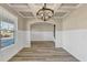 Open dining room featuring wainscotting, hardwood floors, modern chandelier, and stairs to upper level at 1734 Cadence St, Locust Grove, GA 30248