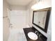 Bathroom featuring a shower-tub combo, black vanity, and white tiled floors at 2084 North Rd, Snellville, GA 30078