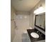 Bathroom featuring a shower-tub combo, black vanity, and white tiled floors at 2084 North Rd, Snellville, GA 30078