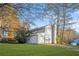 View of the home and garage with a long driveway surrounded by a well-kept lawn and beautiful autumn trees at 4704 Keighley Dr, Stone Mountain, GA 30083