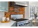 Close-up of the kitchen's stainless steel gas range with brick backsplash and utensil rack at 513 Saint Charles Ne Ave, Atlanta, GA 30308