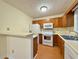 Efficient kitchen featuring wood cabinetry, white appliances, and a breakfast bar at 3533 Mulberry Way, Duluth, GA 30096