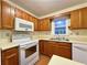 A kitchen featuring wooden cabinets, white appliances, a double basin sink, and a window at 3533 Mulberry Way, Duluth, GA 30096