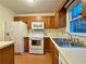 A kitchen featuring wooden cabinets, white appliances, a double basin sink, and vinyl floors at 3533 Mulberry Way, Duluth, GA 30096