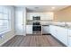 Well-lit kitchen boasts stainless steel appliances, light granite countertops, bright white cabinets, and wood floors at 433 Kara Ln, Mcdonough, GA 30253