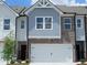 Charming townhome featuring a two-car garage, brick accents, and light blue shingle siding at 541 Tuskegee St # 49, Mcdonough, GA 30253