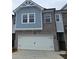 Charming townhome with a white garage door, black hardware, brick and shingle siding, and a well-kept concrete driveway at 541 Tuskegee St # 49, Mcdonough, GA 30253