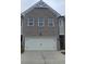 Two car garage beneath a two-story townhome with grey brick and a peak roof at 549 Tuskegee St, Mcdonough, GA 30253