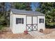 A charming shed with a grey roof and double doors sits amidst lush greenery, offering storage and curb appeal at 2785 Old Sewell Rd, Marietta, GA 30068