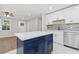 Kitchen view, showcasing a blue island, white cabinets, modern backsplash and wood floors in the adjoining room at 612 Saddlewood Dr, Lawrenceville, GA 30043